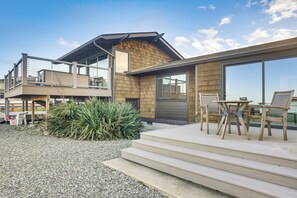 Ein modernes Haus mit Terrasse, Sitzgelegenheit im Freien und einem großen Fenster.