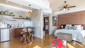 Una cocina moderna con comedor, un dormitorio con cama y mesita de noche, y una sala de estar con sofá y mesa de centro.