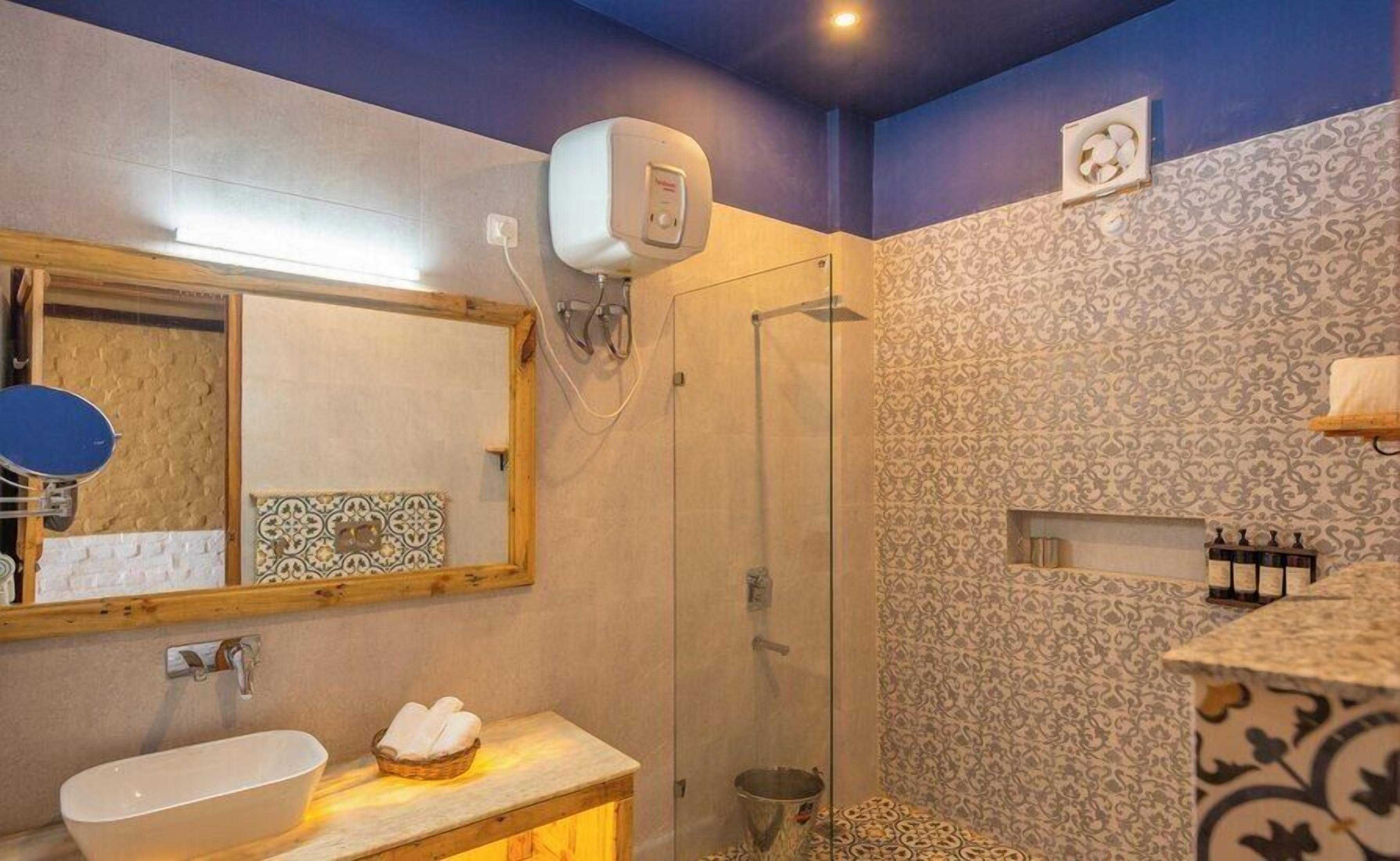 A bathroom with a sink, mirror, shower, and patterned walls.