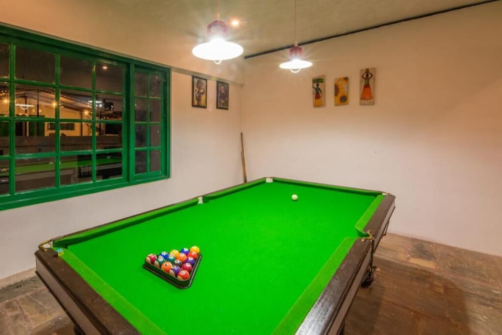 Een biljart met ballen, een raam met groene kaders en plafondverlichting.