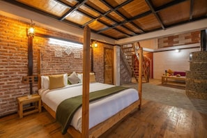 Ein Zimmer mit Himmelbett, Holzboden, Backsteinwänden und einer Treppe.