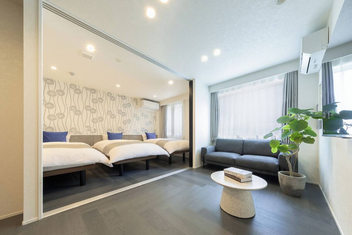 A modern hotel room with a sofa, a round coffee table, and a potted plant.