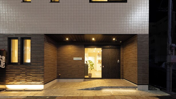 Un bâtiment avec une façade recouverte de carreaux, une porte d’entrée en bois et une enseigne Coca-Cola.