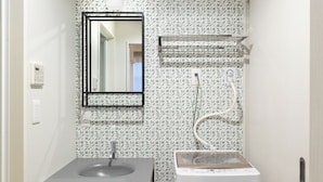 Une petite salle de bain comprenant un lavabo, un miroir, un porte-serviettes et un lave-linge blanc.