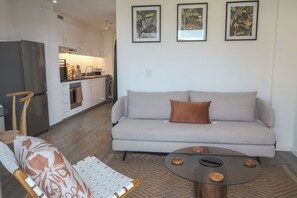 A modern living room with a sofa, a coffee table, and a chair. - Chic 1-Bedroom Retreat with Mountain Views (Cape Town)