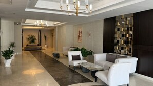 Un vestíbulo moderno con candelabro, zona de estar y una pared decorativa.