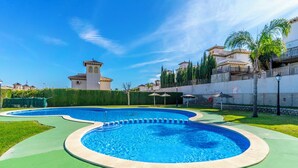 Une piscine au design incurvé, entourée d’une terrasse verdoyante et d’un petit muret.