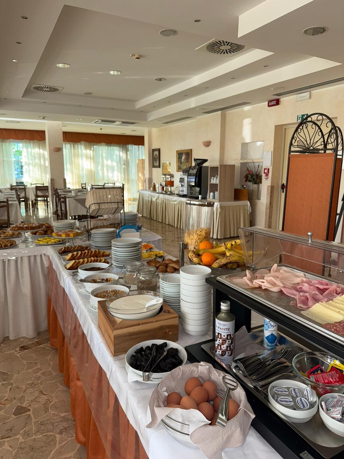 A buffet with various food items, a coffee machine, and a door with a decorative metal design.
