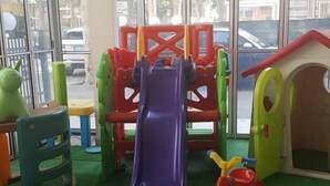 Zona infantil con tobogán, estructuras para escalar y una casita.
