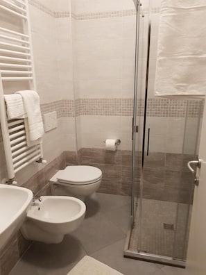 A bathroom with a shower, toilet, bidet, and a towel rack. - Hotel de la Plage (Rimini)