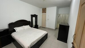 Une chambre à coucher comprenant un lit, une commode, un miroir, une armoire et une porte.