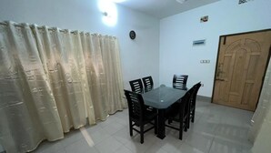 Un espace repas comprenant une table et des chaises, un ventilateur de plafond, un luminaire, une porte et un rideau.