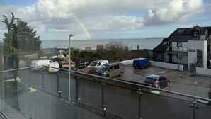 A parking area with vehicles, a building labeled 'The Terrace,' and a view of the sea with clouds and a rainbow. - Clearwater Seaview a perfect retreat (St Ives)