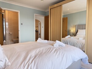 Ein Hotelzimmer mit einem großen Bett, einem Badezimmer mit Dusche und einem Spiegel, der den Raum reflektiert.