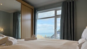 A hotel room with a large bed, a view of the sea, and a chandelier. - Clearwater Seaview a perfect retreat (St Ives)