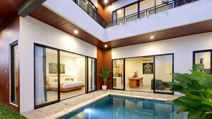 Una casa moderna de dos pisos con piscina, un dormitorio con una cama grande y un comedor con mesa y sillas.