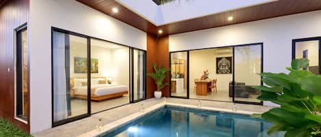 A modern two-story house with a swimming pool, a bedroom with a large bed, and a dining area with a table and chairs.