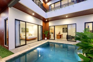 Una casa moderna de dos pisos con piscina, un dormitorio con una cama grande y un comedor con mesa y sillas.