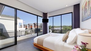 Un dormitorio moderno con una cama grande, un televisor de pantalla plana y un balcón con vistas a edificios.