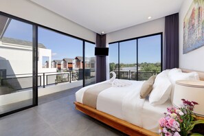 Un dormitorio moderno con una cama grande, un televisor de pantalla plana y un balcón con vistas a edificios.