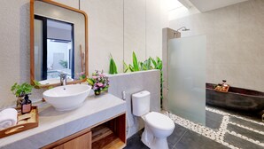 Un baño moderno con un espejo grande, un lavamanos blanco, un inodoro y una zona de ducha con mampara de vidrio.