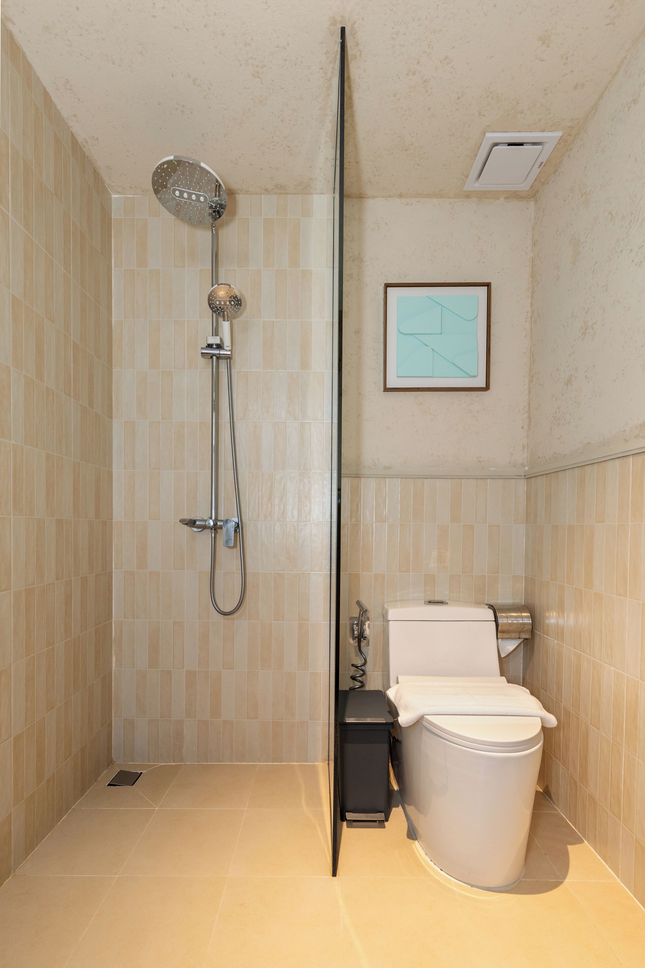 A bathroom with a shower, toilet, and a framed picture on the wall.