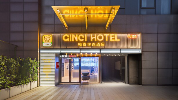 L’extérieur de l’hôtel Ginci, avec son enseigne au néon, ses portes vitrées et sa façade moderne.