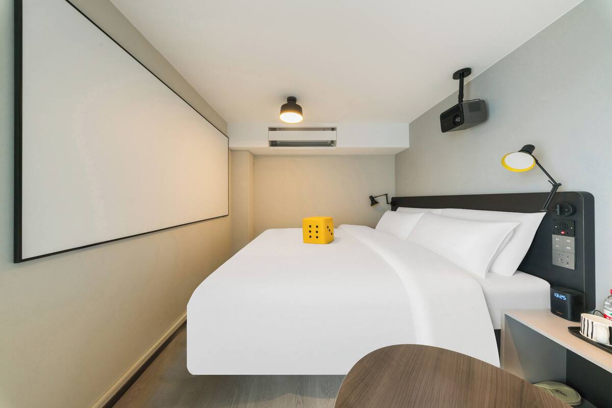 Une chambre d’hôtel moderne équipée d’un lit, d’une table de chevet, d’une lampe et d’un appareil de climatisation.