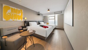 Une chambre d’hôtel avec un lit, un canapé, une petite table et une grande fenêtre.