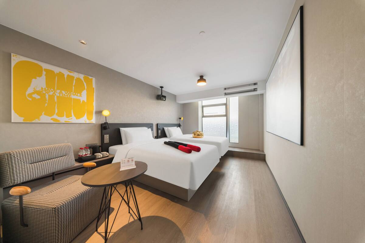 Une chambre d’hôtel avec un lit, un canapé, une petite table et une grande fenêtre.