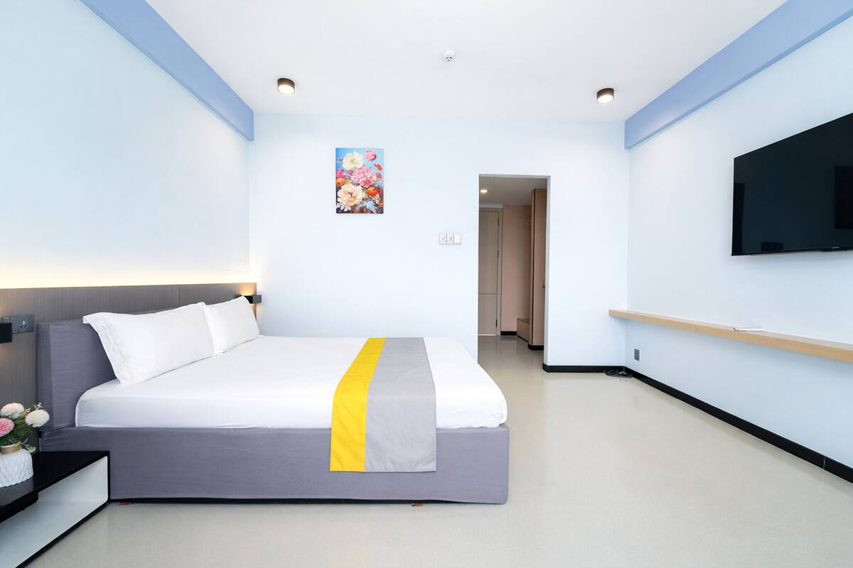 A modern hotel room with a large bed, a flat-screen TV, and a minimalist design.