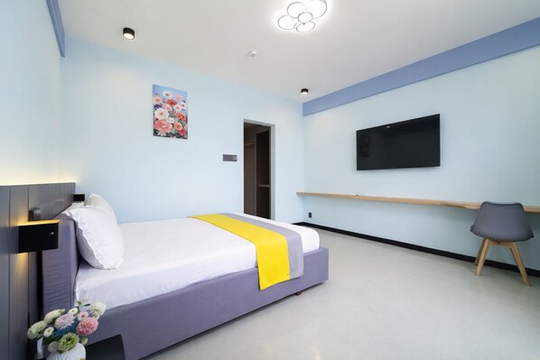 Une chambre d’hôtel moderne équipée d’un lit, d’un téléviseur à écran plat, d’un bureau et d’un tableau au mur.