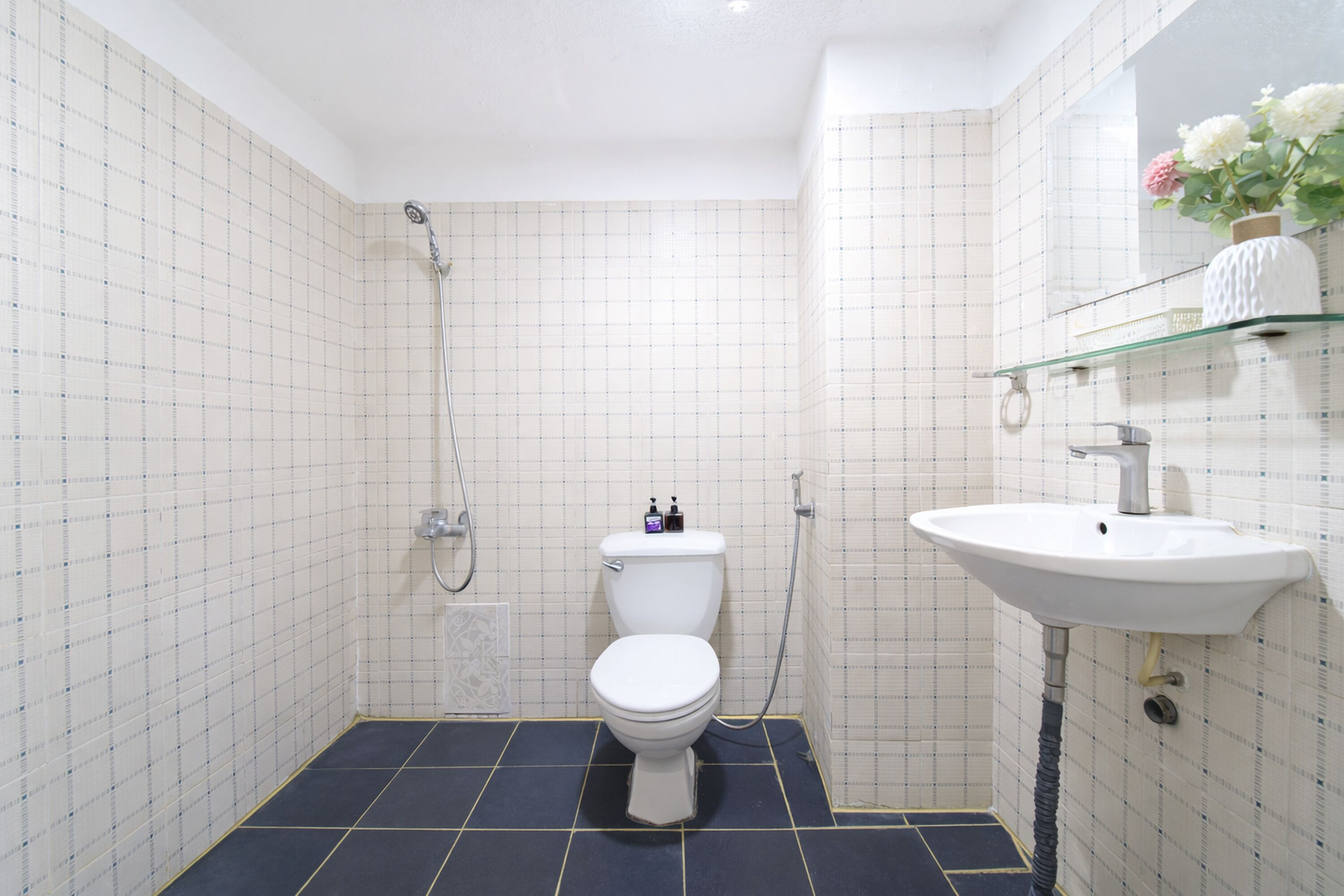 A bathroom with a toilet, shower, and sink.