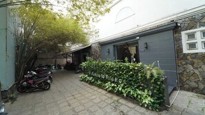 A courtyard with a stone wall, a motorcycle, and a covered area with a door. - Palette Amura Hotel - Near Gigamall (Ho Chi Minh City)