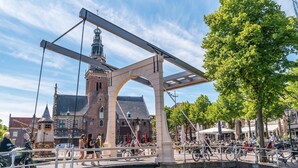 A historic bridge with a tower, a canal, and a bustling outdoor café area. - Alkmaar Cozy Dutch Villa (West-Graftdijk)