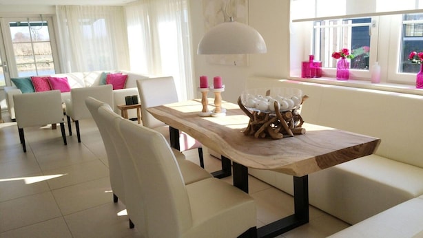 A modern living room with a dining table, white sofas, and a large window with curtains. - Alkmaar Cozy Dutch Villa (West-Graftdijk)
