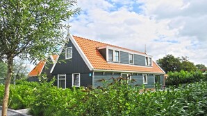 A two-story house with a steeply pitched roof, a dark exterior, and a garden in the foreground. - Alkmaar Cozy Dutch Villa (West-Graftdijk)