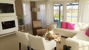 A living room with a fireplace, white sofas, a coffee table, and a TV mounted on the wall. - Alkmaar Cozy Dutch Villa (West-Graftdijk)