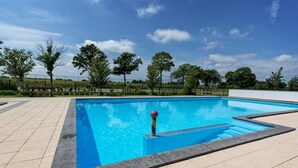 A rectangular swimming pool with clear blue water, surrounded by a tiled deck and a low fence. - Alkmaar Cozy Dutch Villa (West-Graftdijk)