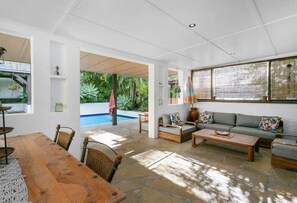A spacious living area with a pool, a dining table, and a sofa set. - Burleigh Coastal Escape 4BR Home (Burleigh Heads)