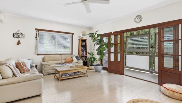 A living room with a sofa, coffee table, and potted plants. - Burleigh Coastal Escape 4BR Home (Burleigh Heads)