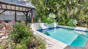 A swimming pool with a pergola and tropical plants. - Burleigh Coastal Escape 4BR Home (Burleigh Heads)