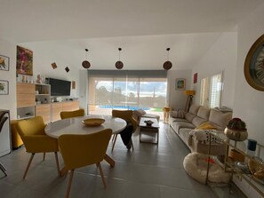 A modern living room with a dining area, a sofa, a coffee table, and a TV. - Casa Can Pep in Begur (Begur)