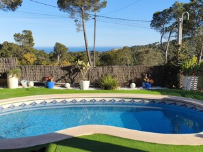 A swimming pool with a tiled edge, surrounded by a grassy area and a wooden fence. - Casa Can Pep in Begur (Begur)