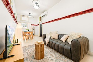 Un salon comprenant un canapé, une table basse, un téléviseur et un coin repas avec des chaises et une table.