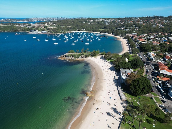 Eine Vogelperspektive einer Küstenregion mit Strand, Booten und Wohngebäuden.