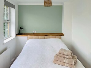 A bedroom with a bed, a window, a bedside lamp, and a wall-mounted light fixture.