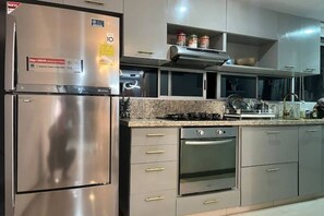 Eine moderne Küche mit Edelstahlgeräten, einer Granitabdeckung und grauen Schränken.