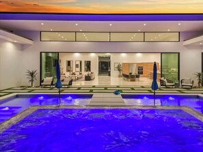 Ein modernes Gebäude mit Pool, großen Fenstern und Blick ins Innere.