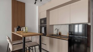 A modern kitchen with a wooden dining table, chairs, a refrigerator, an oven, and a microwave.